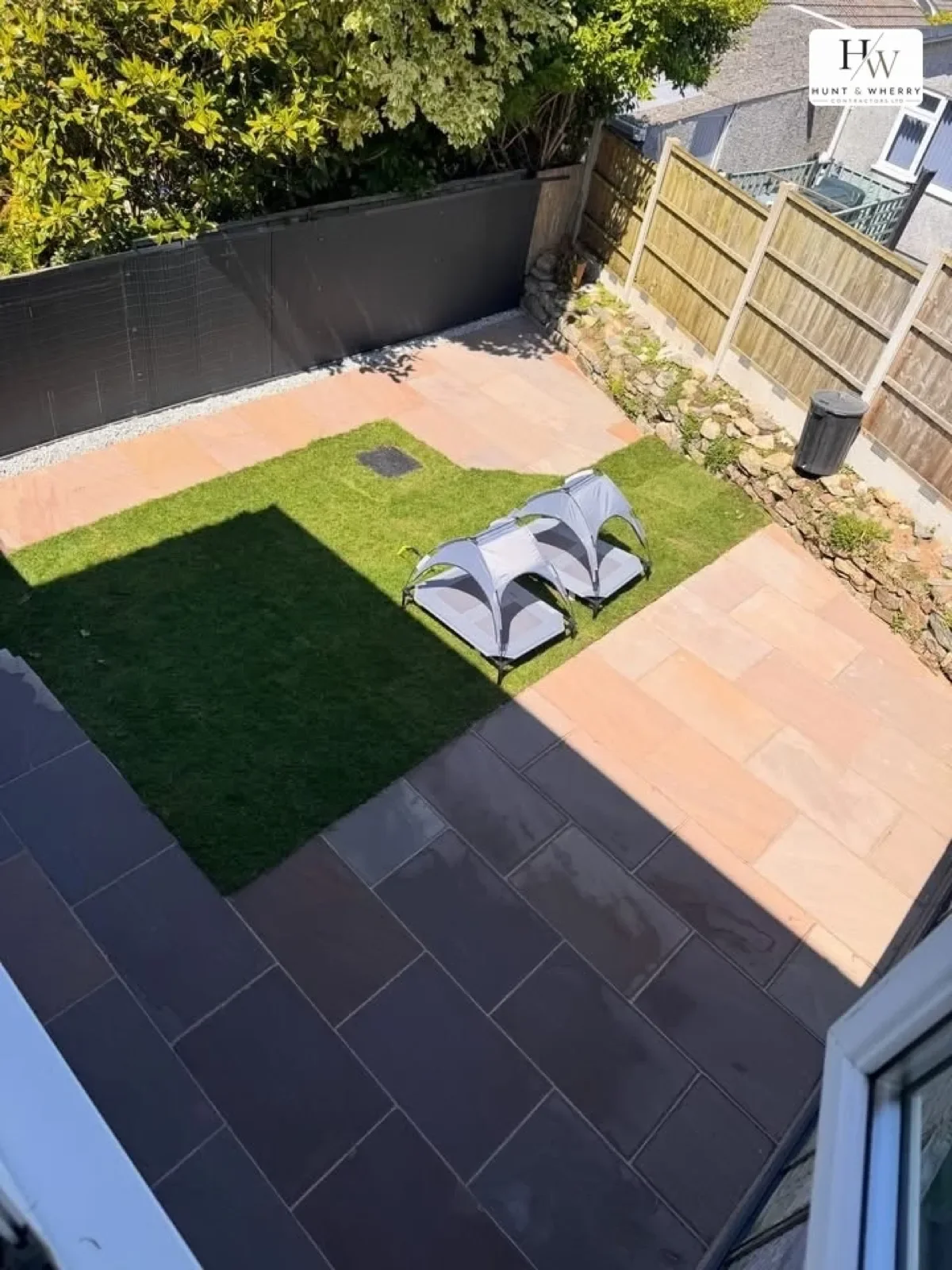 Small garden with artificial turf and sandstone paved border