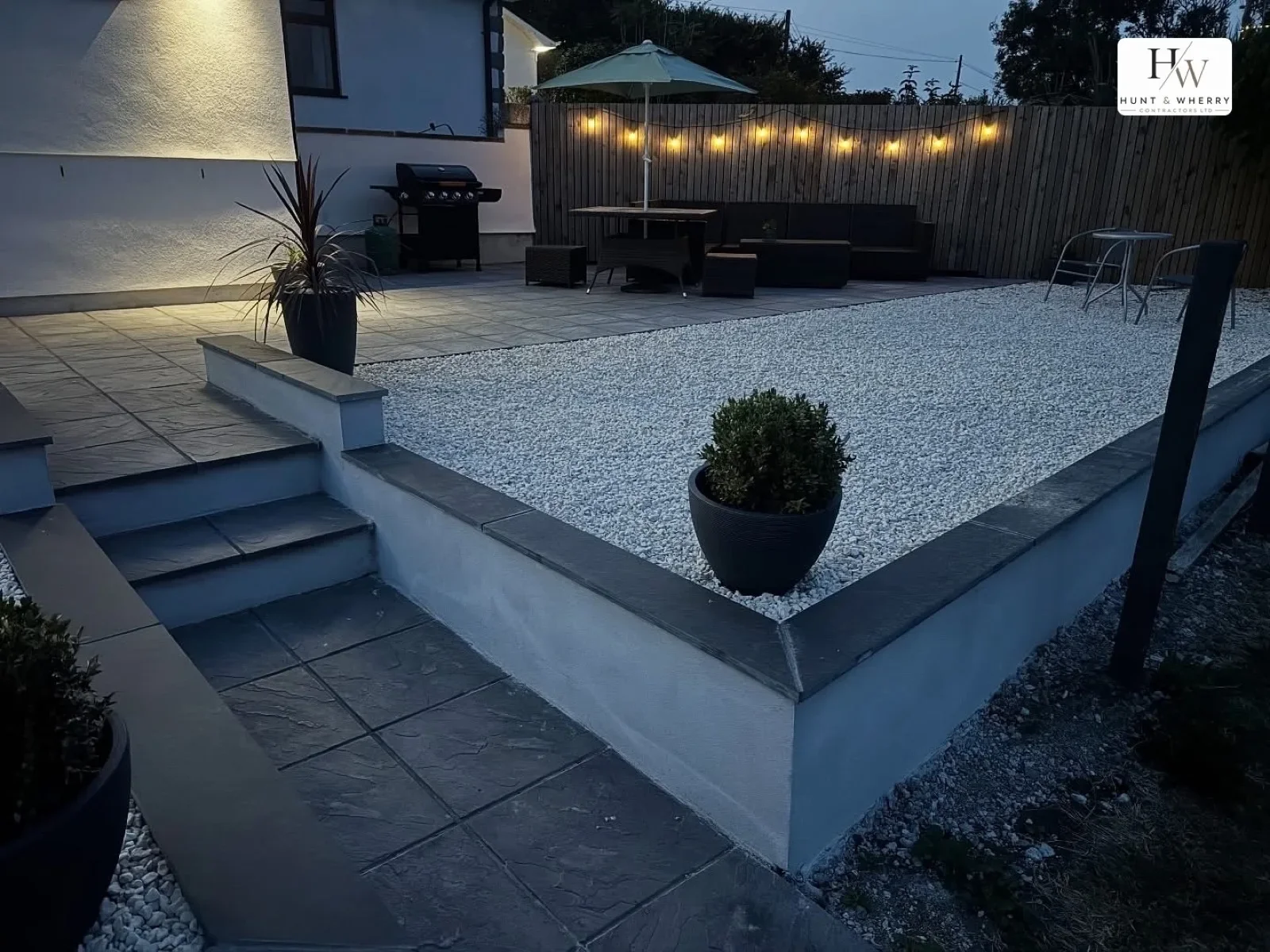 Raised patio with steps and planters lit at dusk
