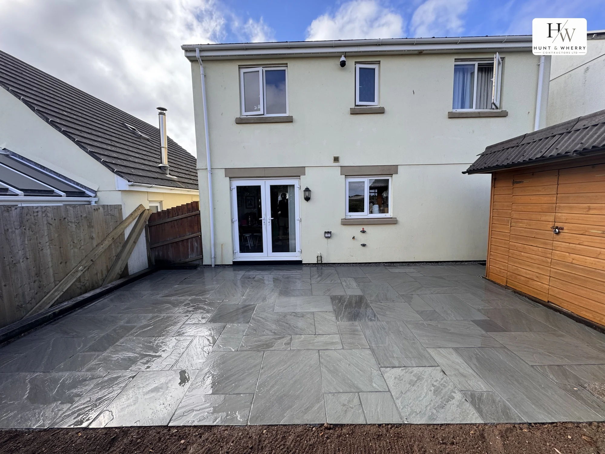 Large riven sandstone patio behind a detached house