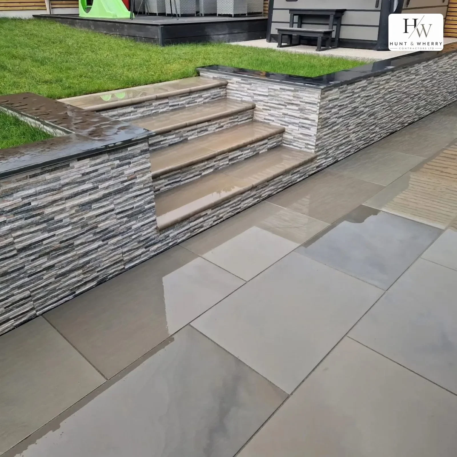 Porcelain paving with split-face stone retaining wall and steps