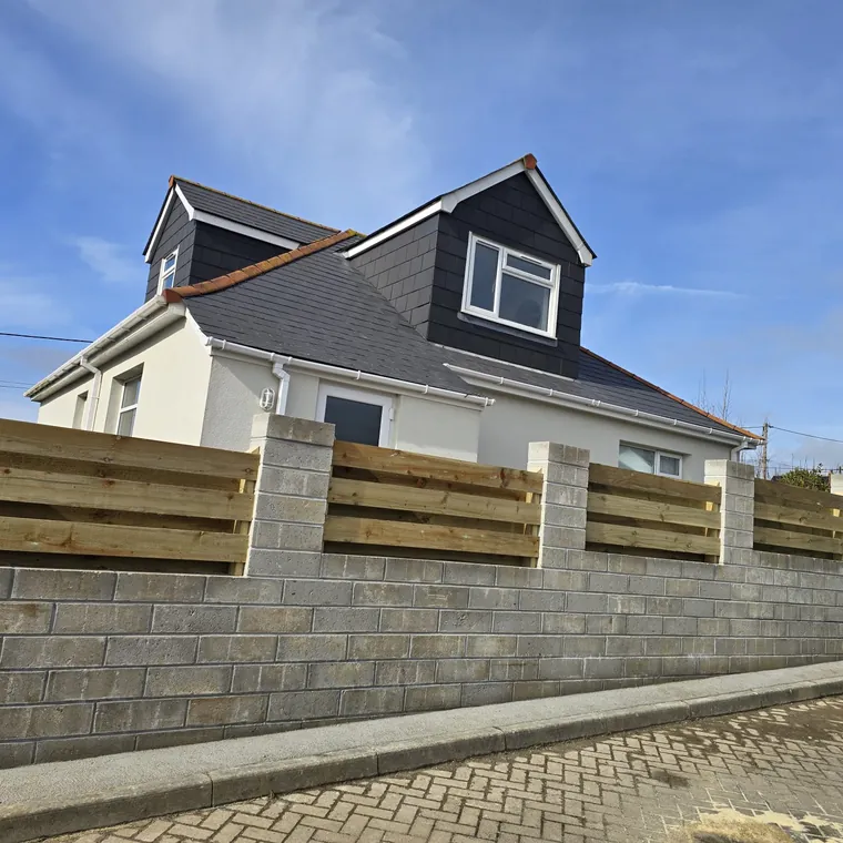 Blockwork retaining wall with a timber fence run above it along a garden boundary