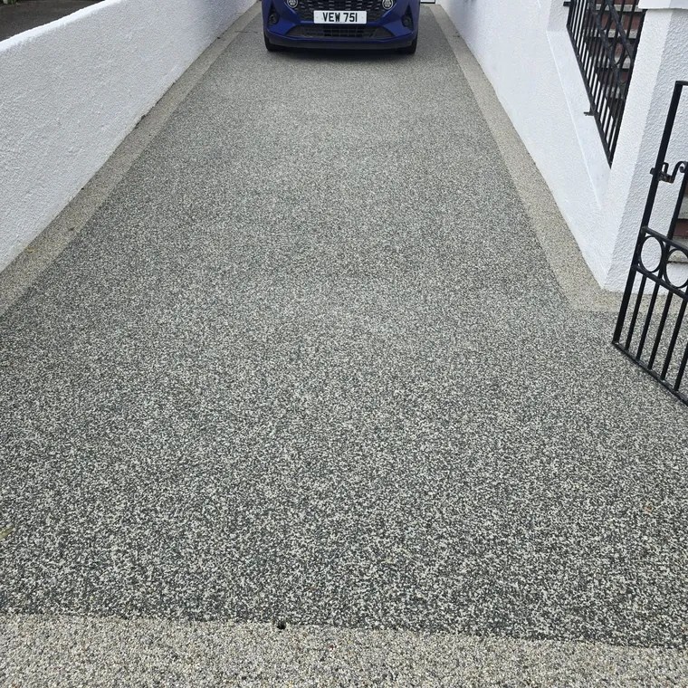 Finished silver resin bound driveway running between rendered garden walls
