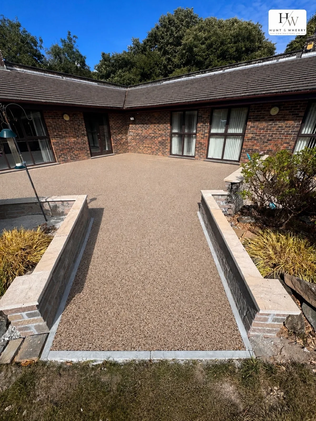 Resin bound path with stone-capped walls leading to a brick bungalow entrance