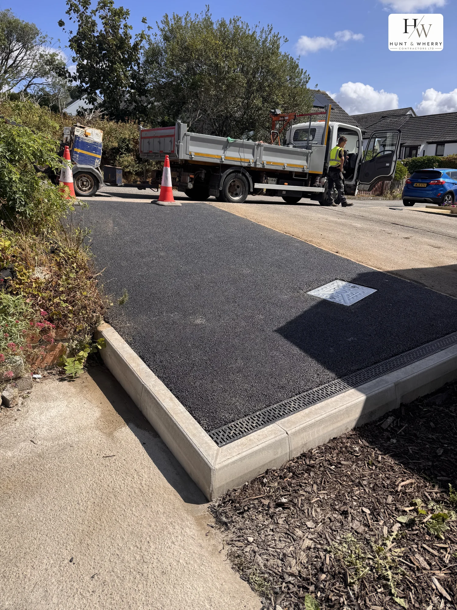 Freshly laid tarmac driveway with new concrete kerb edging