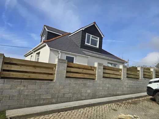 A run of concrete block retaining wall and timber fencing along a drive