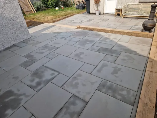 Large format grey sandstone paving laid across a rear patio