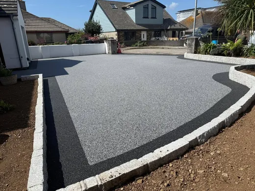Silver resin bound driveway with a charcoal border and rendered walls