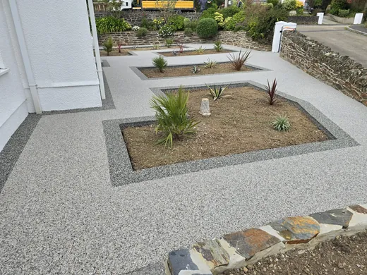 Silver resin bound front garden with planted beds and a slate step