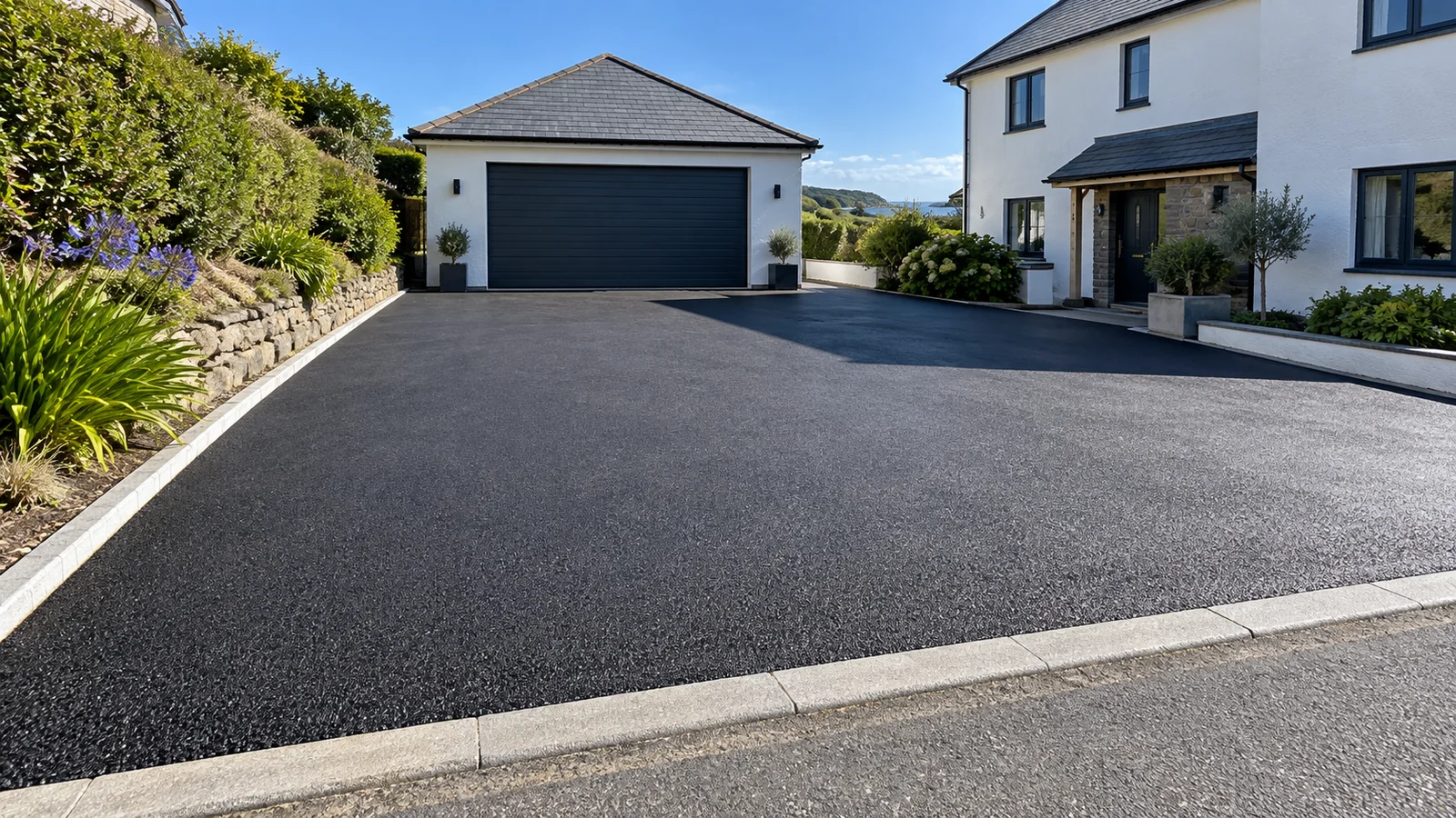 Freshly laid tarmac driveway running between hedges to a house in west Cornwall